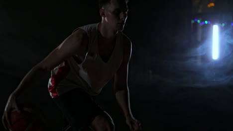 one-young-adult-man,-basketball-player-dribble-ball,-dark-indoors-basketball-court.-Smoke